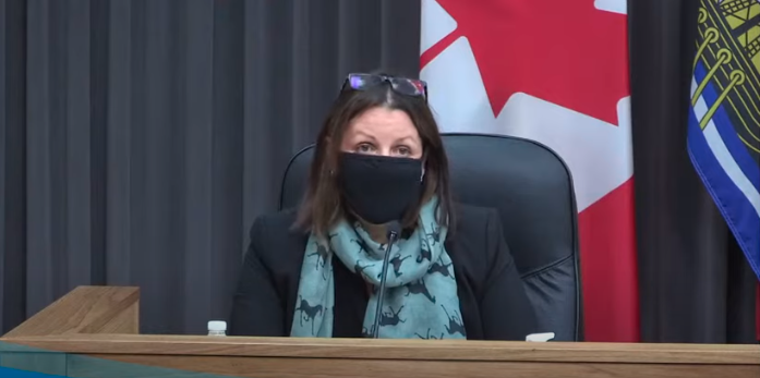 Doctor Jennifer Russell sits behind a desk wearing a face mask.