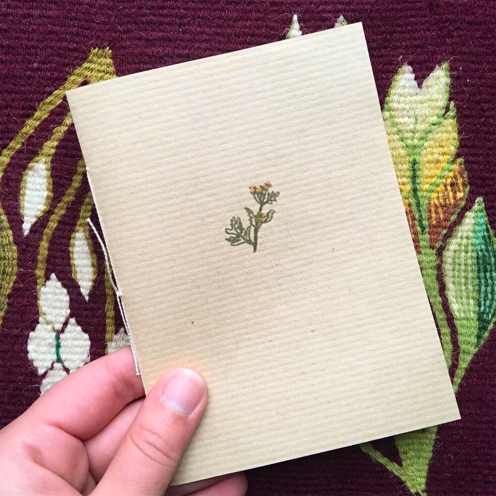 The front cover of a small zine with a hand drawn flower.