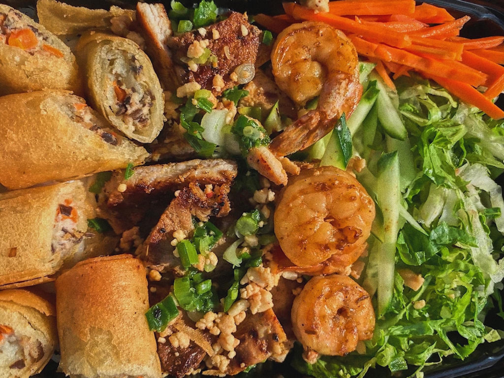 A close up of spring rolls, shrimp, and vegetables.