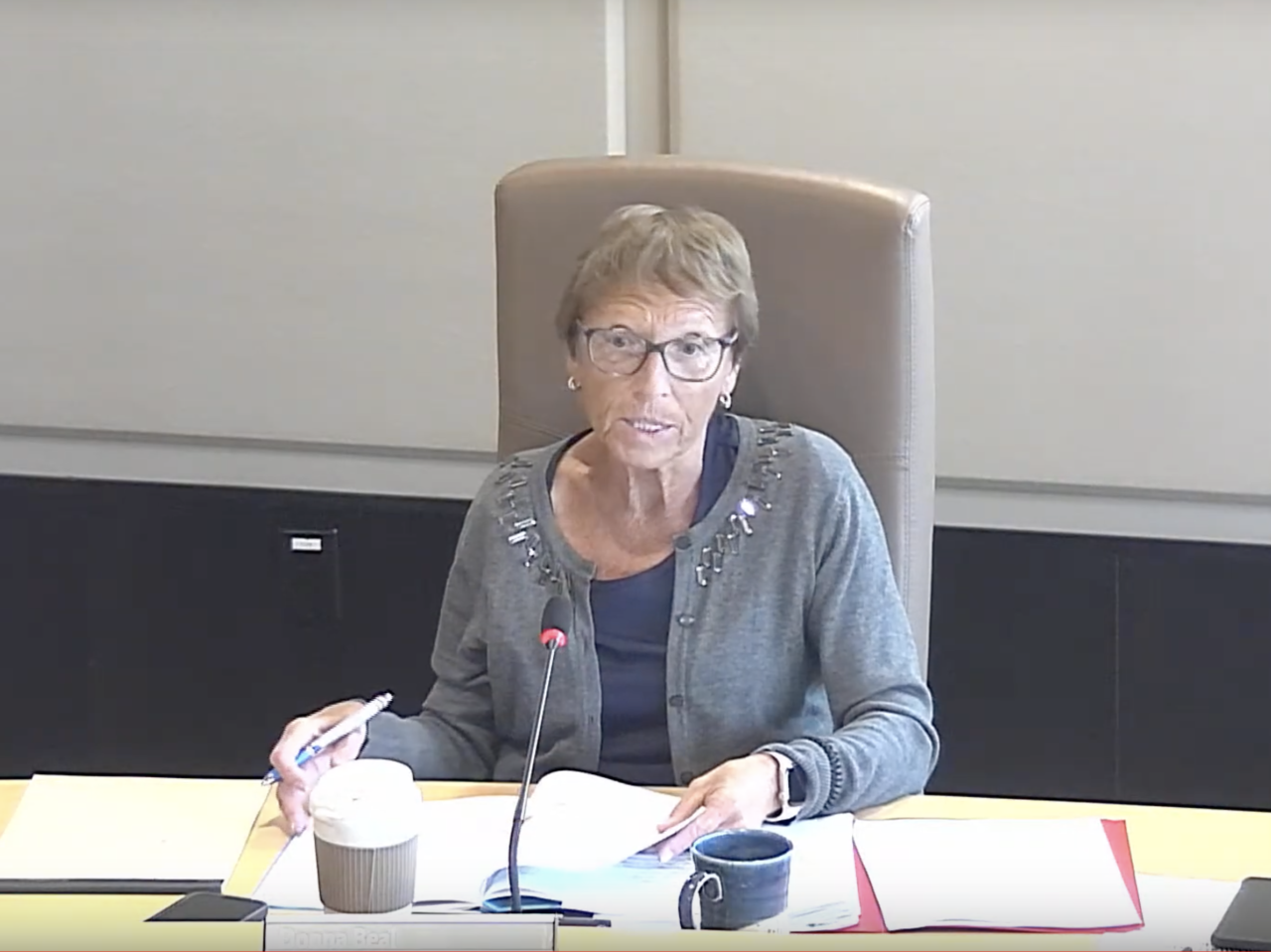 a woman at a council table with lots of papers on her desk