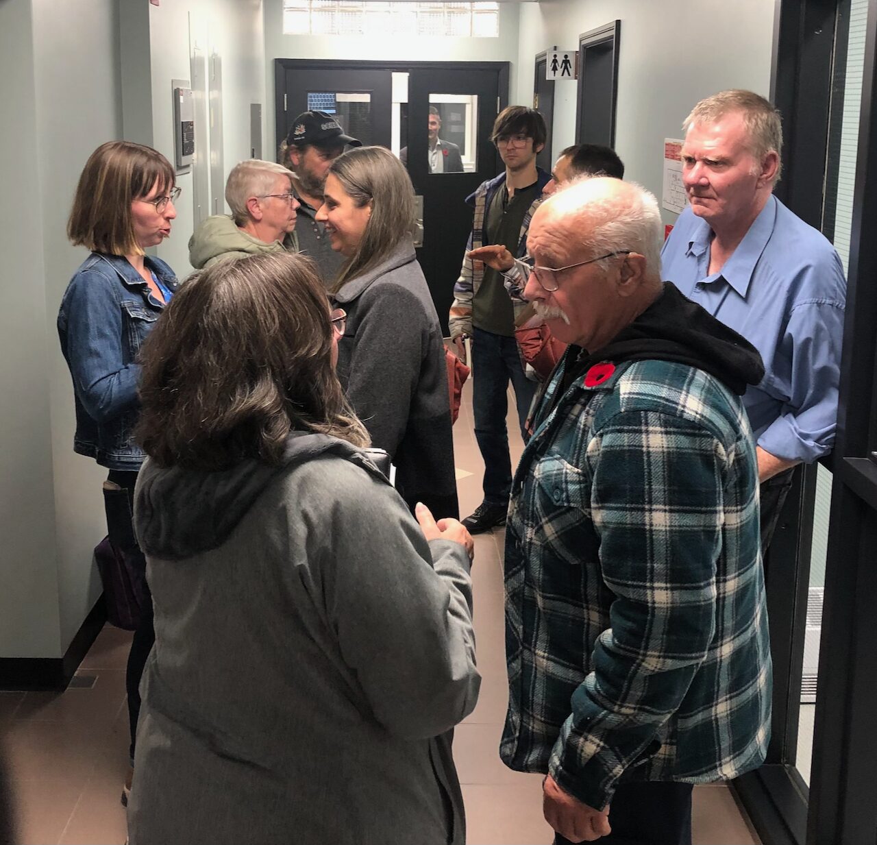 A group of people standing chatting in a hallway
