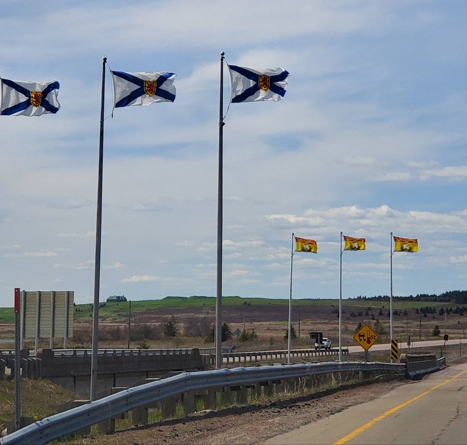 Nova Scotia and New Brunswick flags flying at the provincial border.