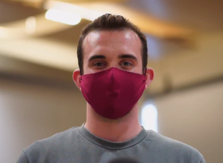 Jon Ferguson wears a red mask and a grey T-shirt. It is clear he is smiling with his eyes.