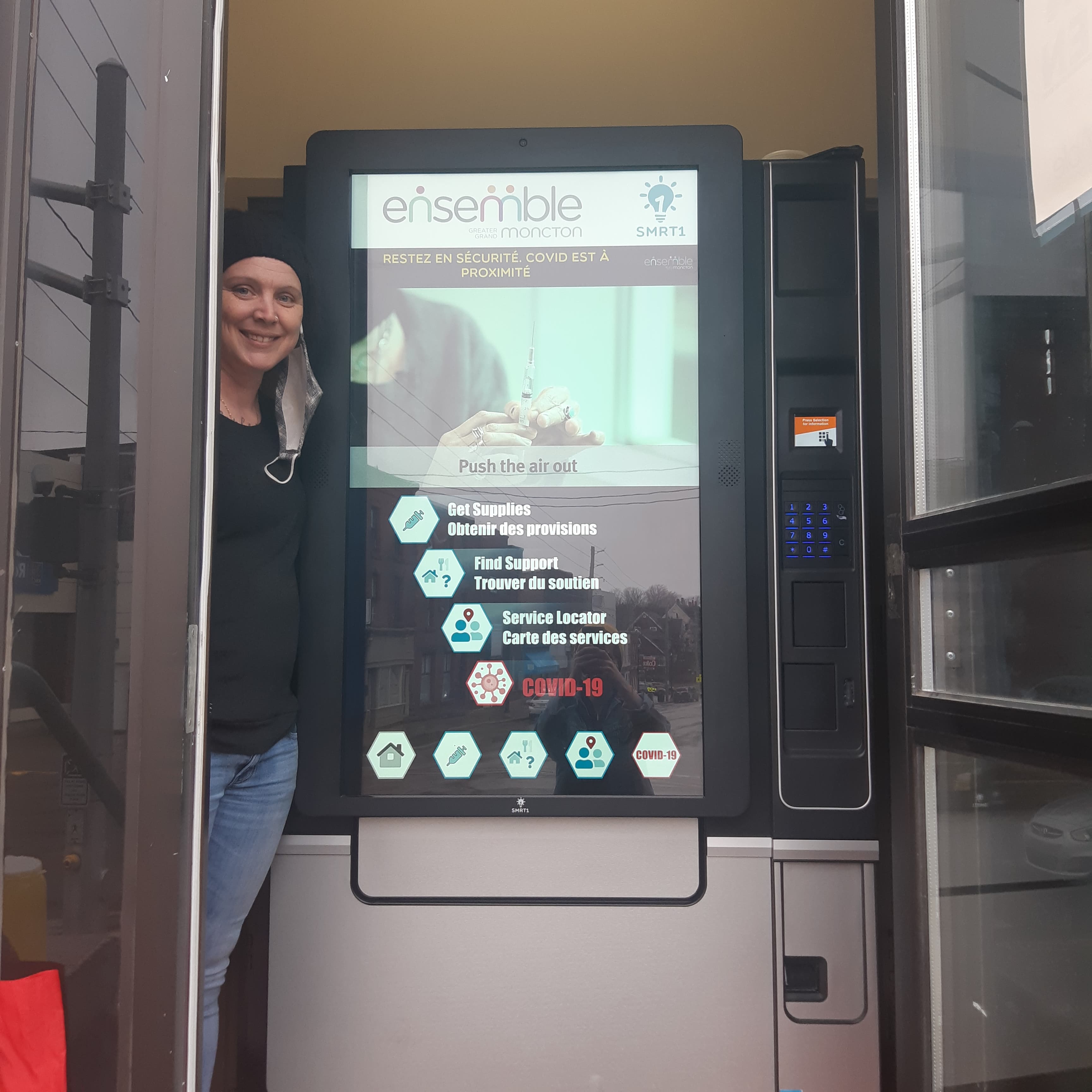 Ashley Legere stands next to an interactive dispensing service machine.