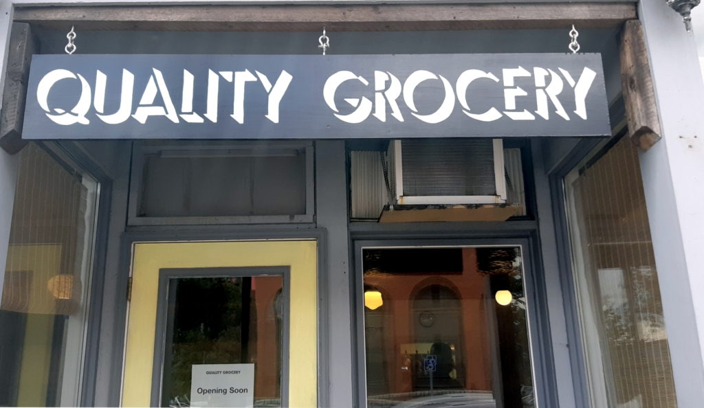 The exterior of a retail building with a sign that reads "Quality Grocery."