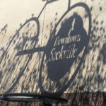 a shadow of a "Downtown Sackville" bike rack on a sidwalk